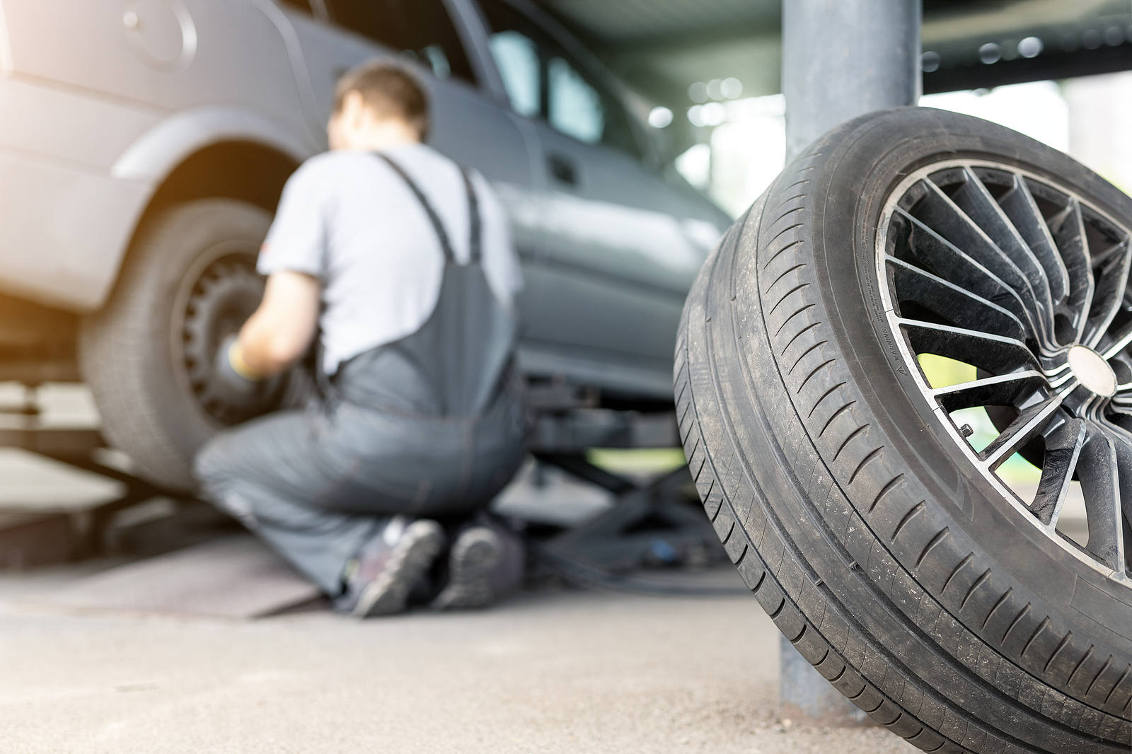 Mechanic replacing and repairing a tyre on a car.